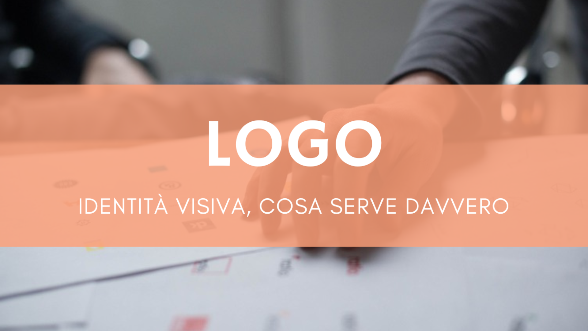 Mano che valuta diverse proposte di logo stampate su carta per l'identità visiva aziendale